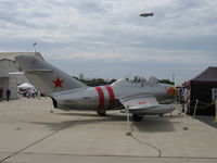 N687 @ CMA - 1953 Mikoyan Gurevich MIG 15UTI tandem trainer 'Red Bull', Klimov VK-1A 5,952 lb st afterburning turbojet. NATO code name Midget. N10A Goodyear 'Spirit of America' Blimp in background sky. - by Doug Robertson