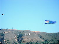  - Banner Tow by N3042M, a 1947 Piper Super Cruiser with uncowled 180 Hp Lycoming-against backdrop of Santa Paula's 2,263' South Mountain with SP marking. Advertising a new upcoming TV program. - by Doug Robertson