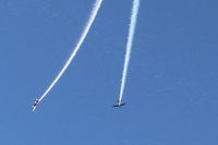  - N144X and N145HR doing a high near-synonymus razzle-dazzle smoke high overhead arrival before landing successively from the Rwy 22 pattern  - by Doug Robertson